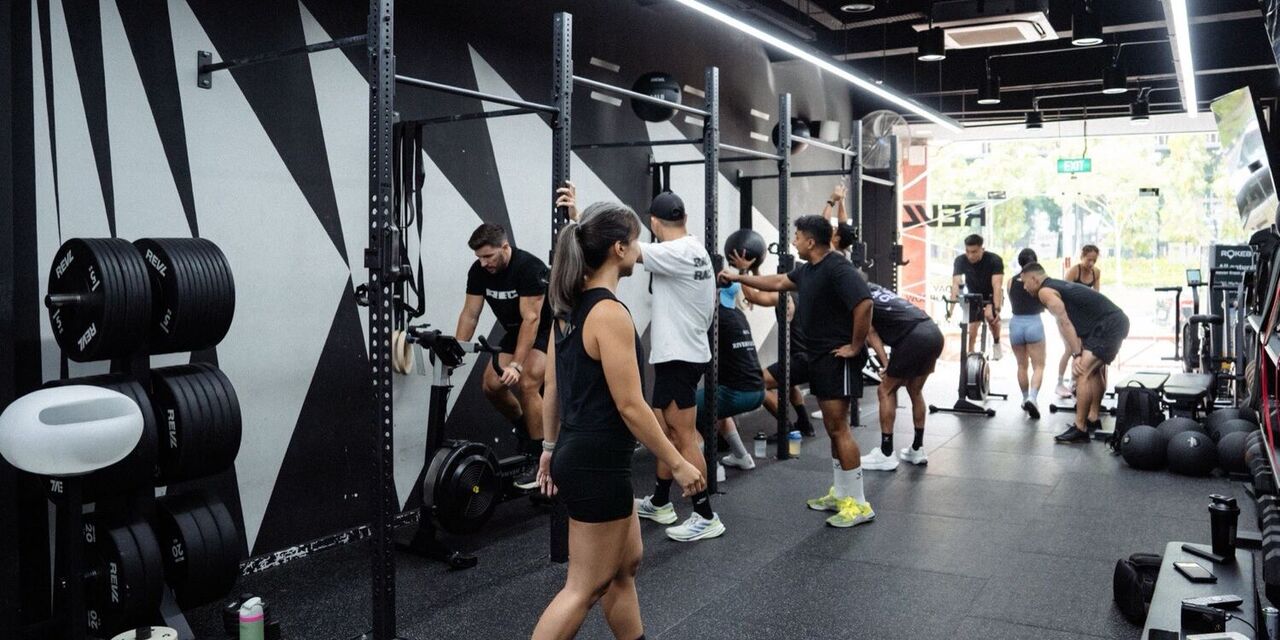 A REVL class mid session: members on a rower, a bike erg and pressing a dead ball overhead