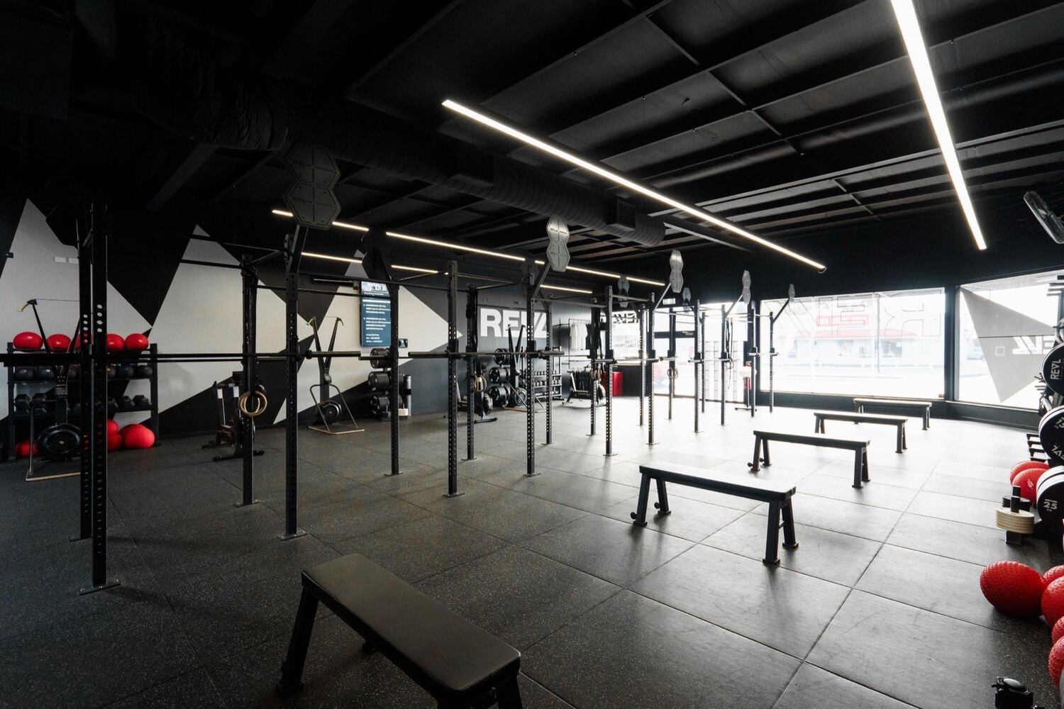 An empty REVL training floor with a long rig of squat racks under linear lighting